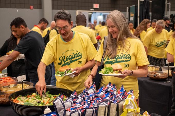 two people getting food from a buffet