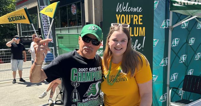 two people posing for a photo, one is waving a small pennant flag