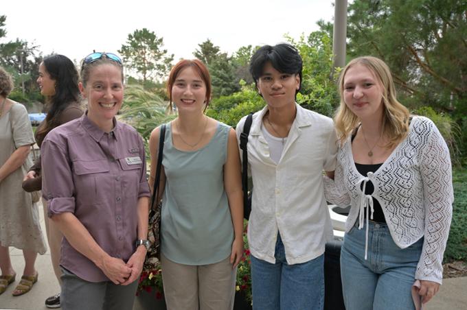 Four people standing outside, looking at camera.