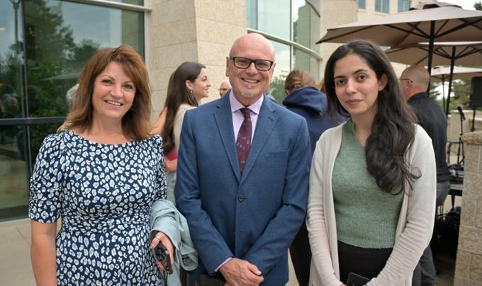 Three people standing outside looking at camera.