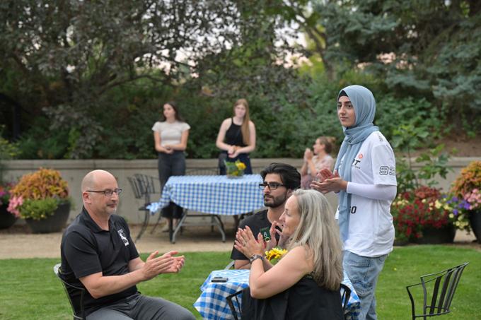 People at outdoor party sitting at tables, standing.