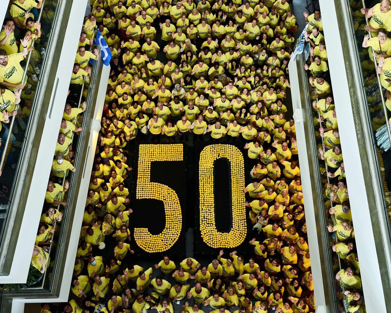 Hundreds of faculty and staff at the U of R stand next to a display table of yellow cupcakes.