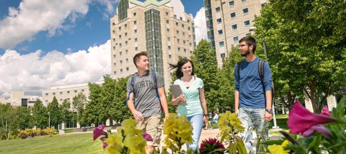 Three university students walking outdoors down path