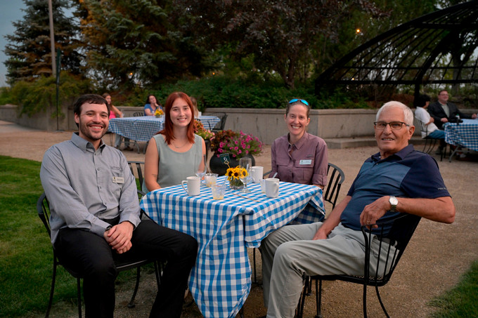 Four people sitting at table outside.