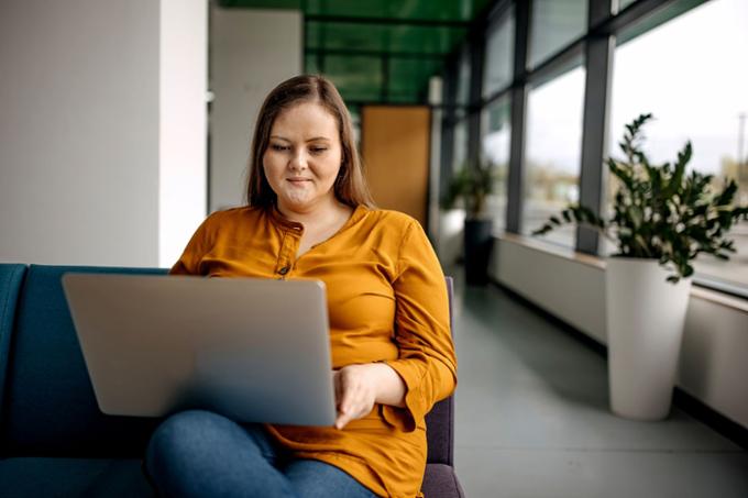 Student wearing a yellow shirt sitting at a table with a laptop.