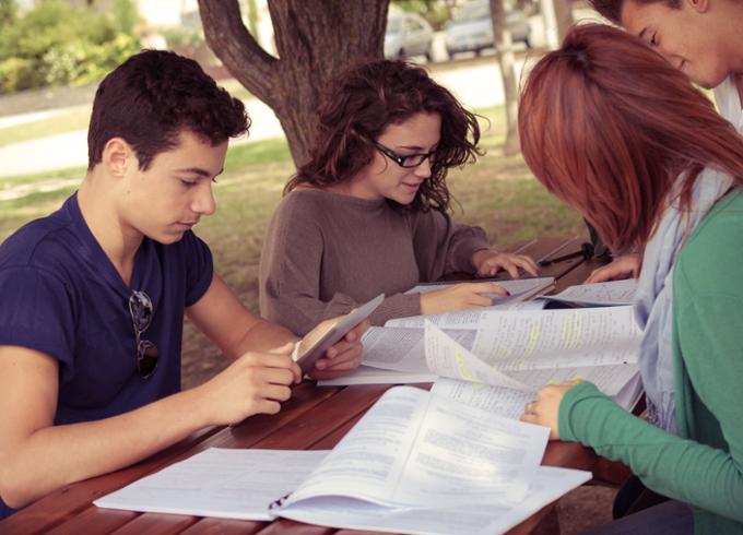 A group of students studying outdoors at a picnic table.