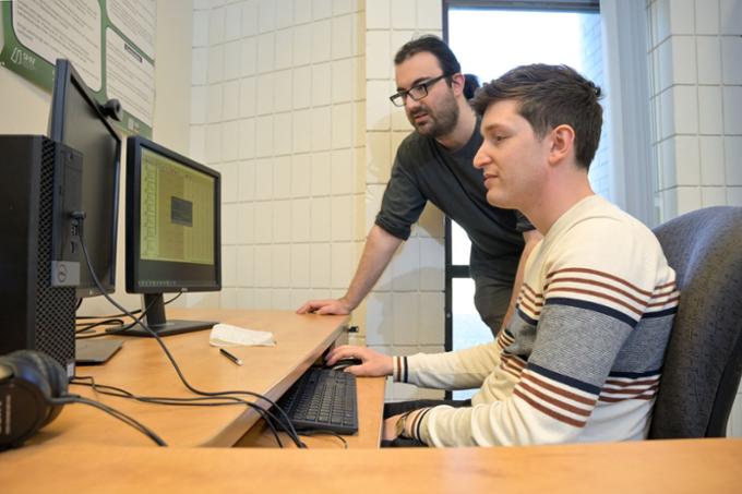 Two graduate students look over data on a computer.