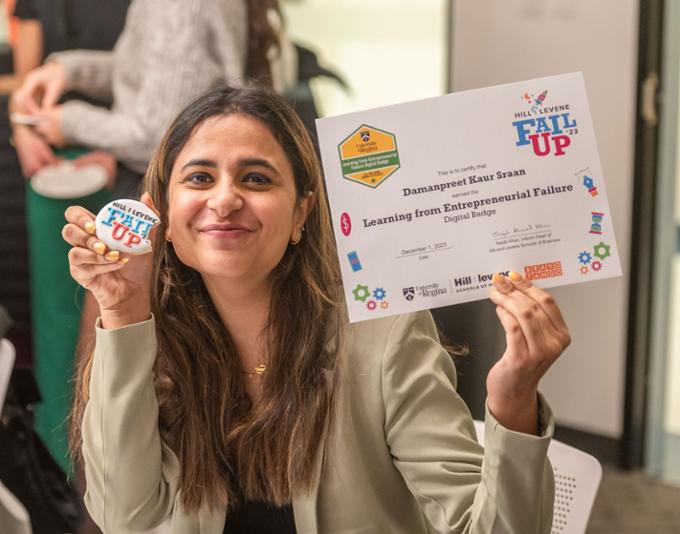 A participant holds up her certificate in one hand and a Fail UP cookie in another.