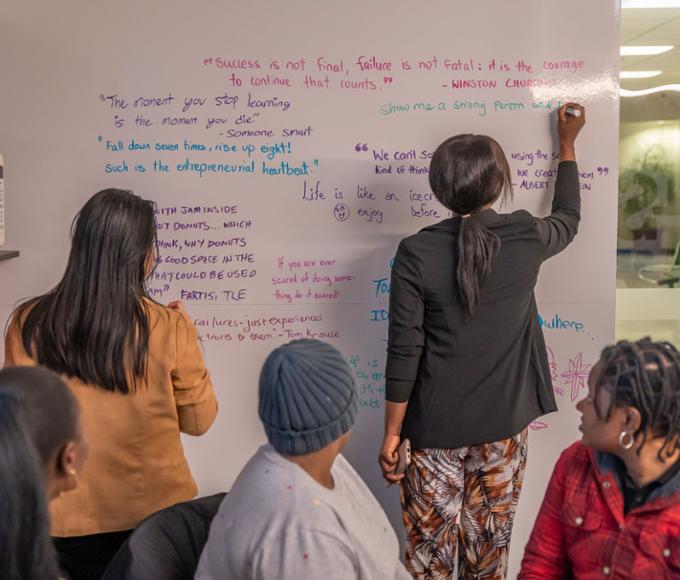 Students are writing their favourite quotes on failure and learning on a whiteboard in the Entrepreneurial Collision Space.