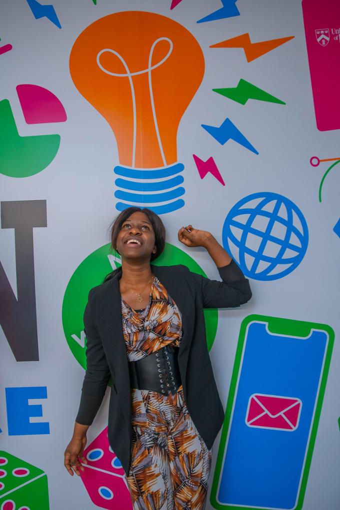 A participant poses with the lightbulb mural on the wall.