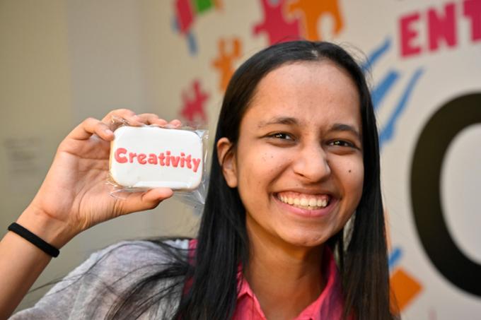 A participant poses with a cookie with the word "Creativity" on it.