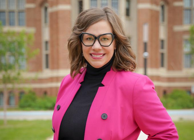 Centre for Continuing Education Dean, Christie Schultz standing in front of the College Avenue Campus wearing a bright pink blazer.