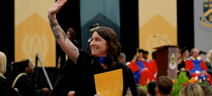 A graduate waving to the crowd