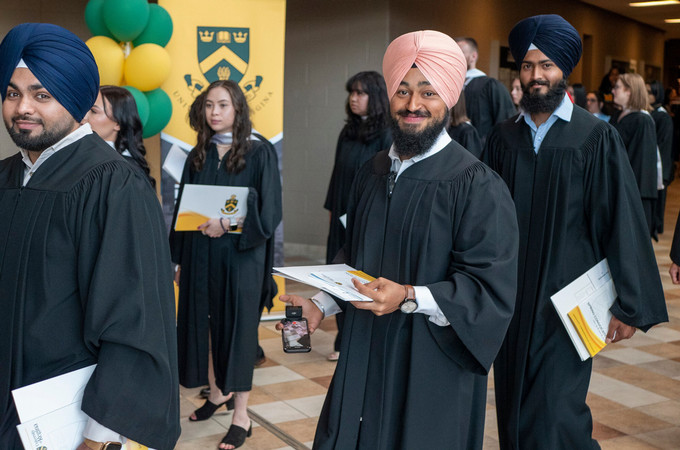 Graduating students in gowns walking in the hallway, going into their convocation ceremony