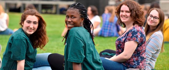 four people sitting on the grass and smiling