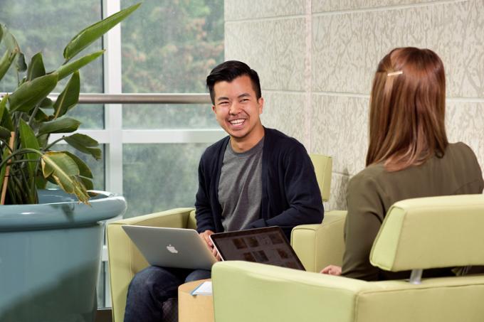 Two smiling students sitting and talking. 