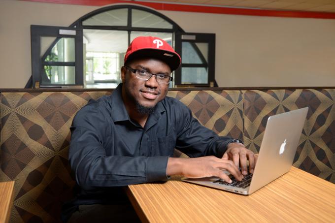 Student at table with laptop open, looking at the camera