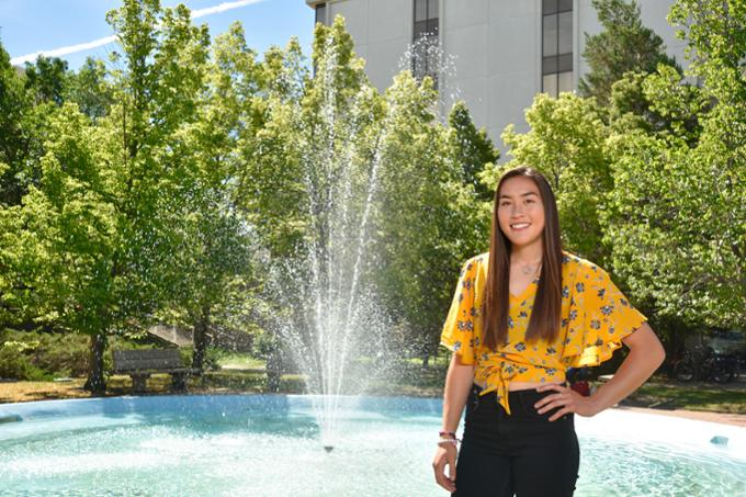 Student poses in front of a fountain