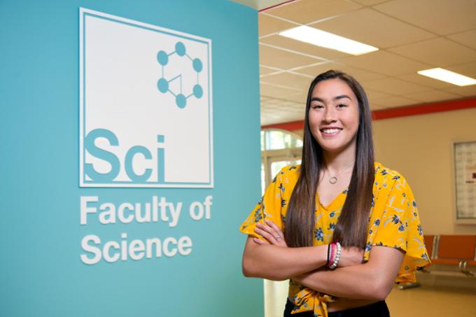 Student poses at a wall on campus