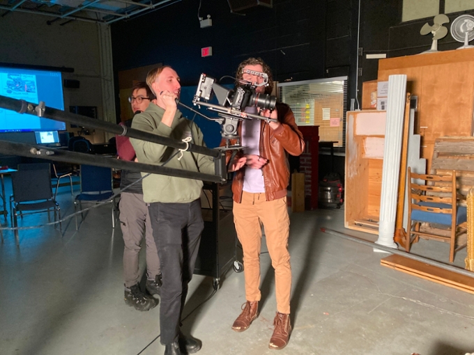 Three students using a camera in a film classroom