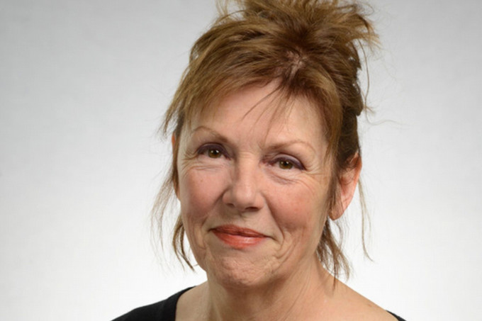 A woman holding a book poses for the camera