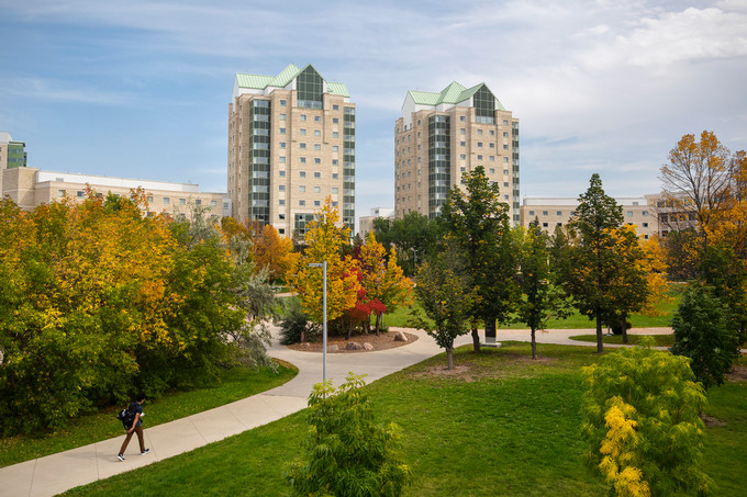 Photograph of the University of Regina campus with student walking on path