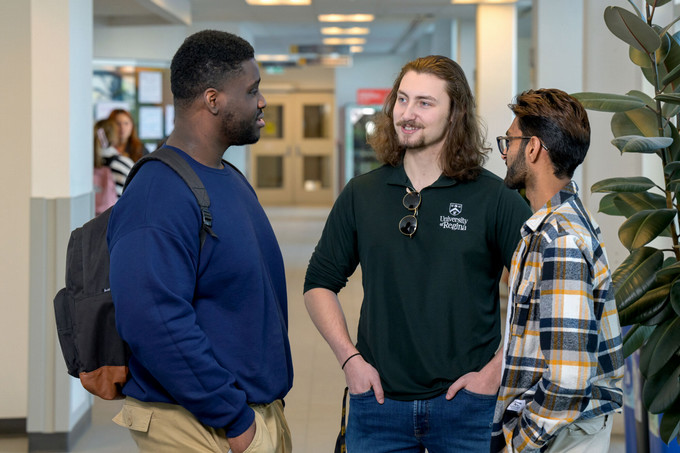 three students visiting in a campus hallway