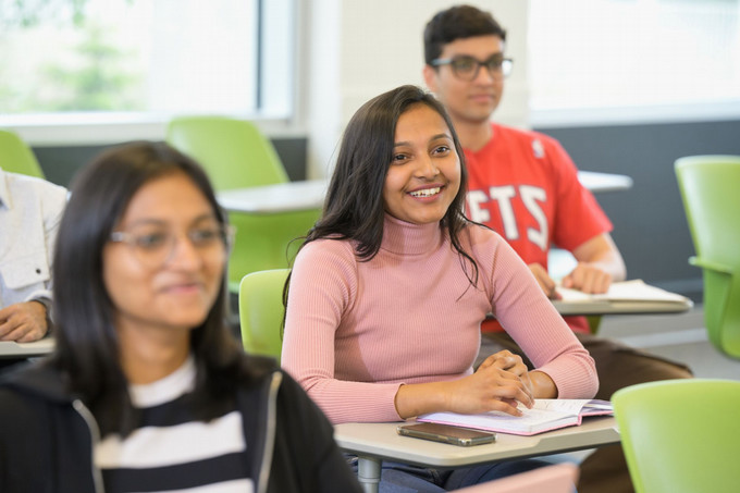 three students sitting at desks in a classroom