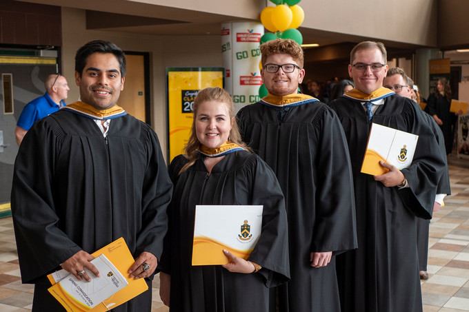 Students at Convocation Wearing Gowns and Holding Diplomas