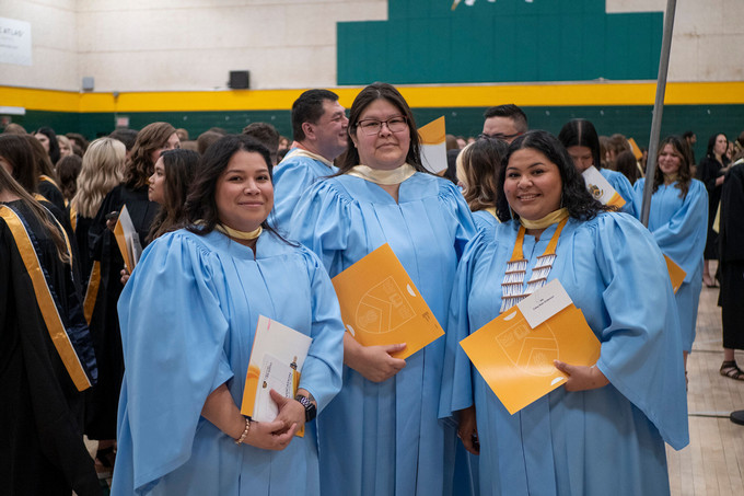 three graduating students in light blue convocation gowns