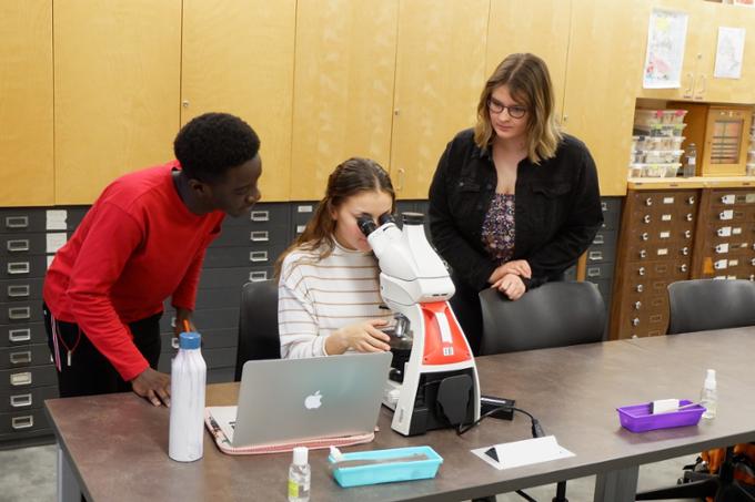 Group of students around a microscope. 