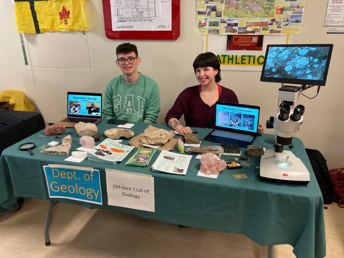 Geology students sitting at an outreach booth. 