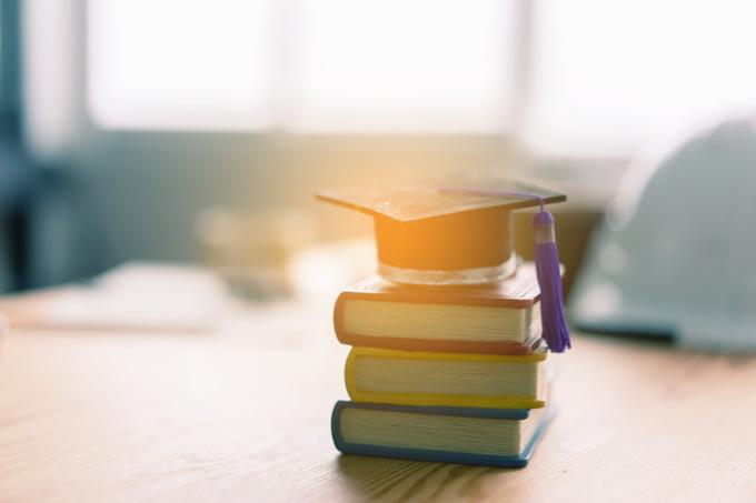 A stack of books with a graduate cap on top. 