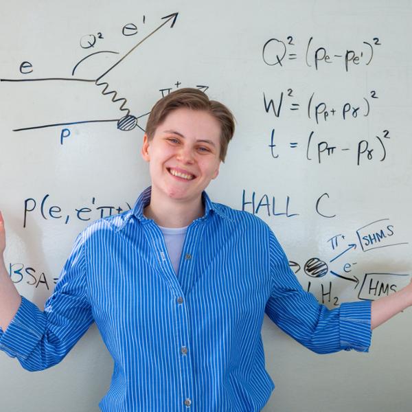 Alicia Postuma stands in front of a board of equations