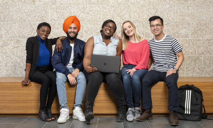 Five students sitting on a bench, smiling