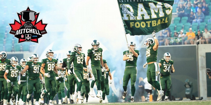 Rams football players running on to the field with a flag