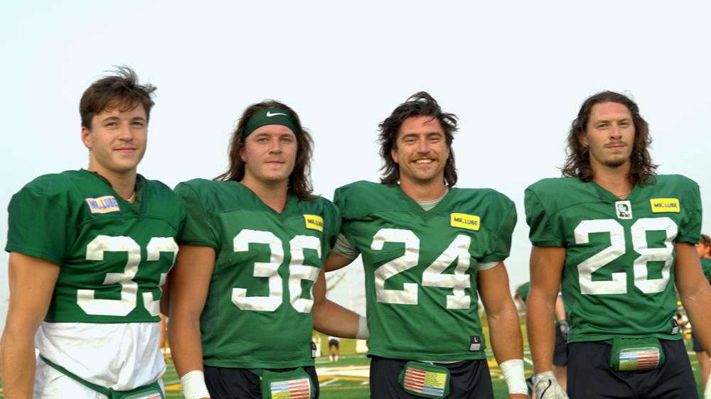 Four football players posing for the camera