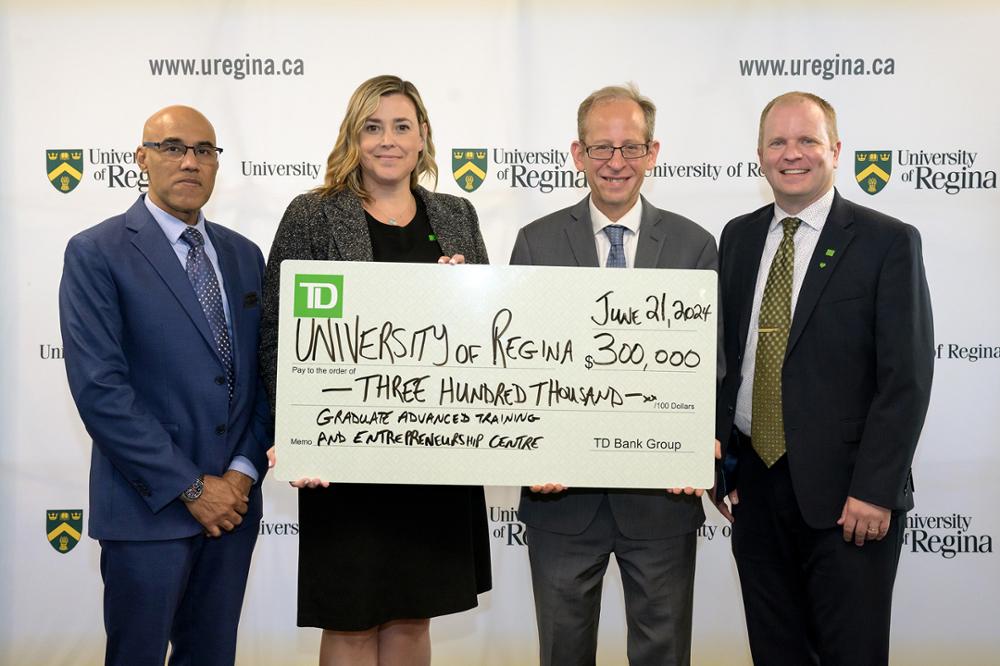 A group of smiling people stand together and hold a novelty-sized cheque.