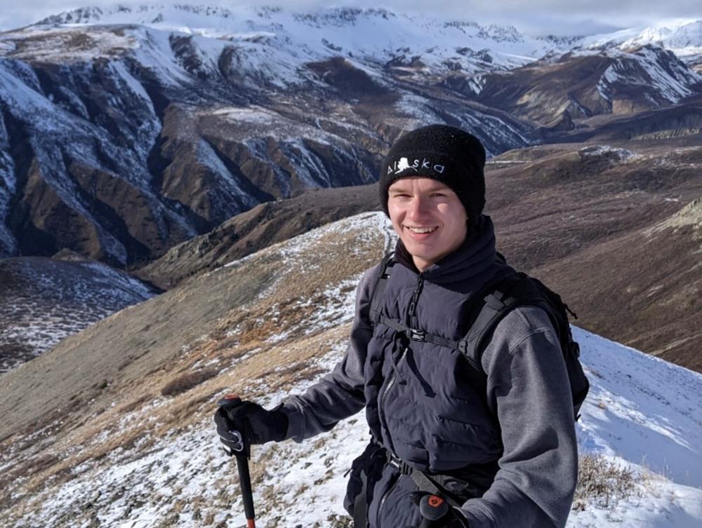 Young man with snow covered mountain in background.