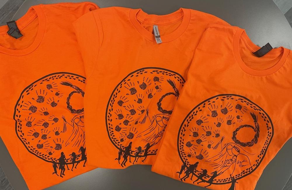 Three orange t-shirts on a table