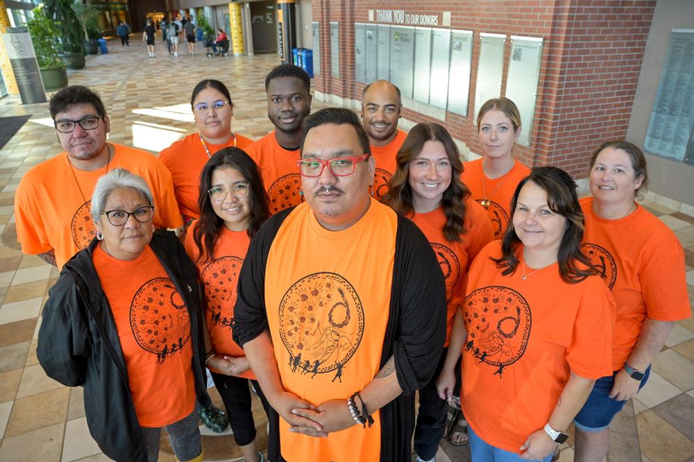 A group of individuals standing in a hallway wearing orange t-shirts