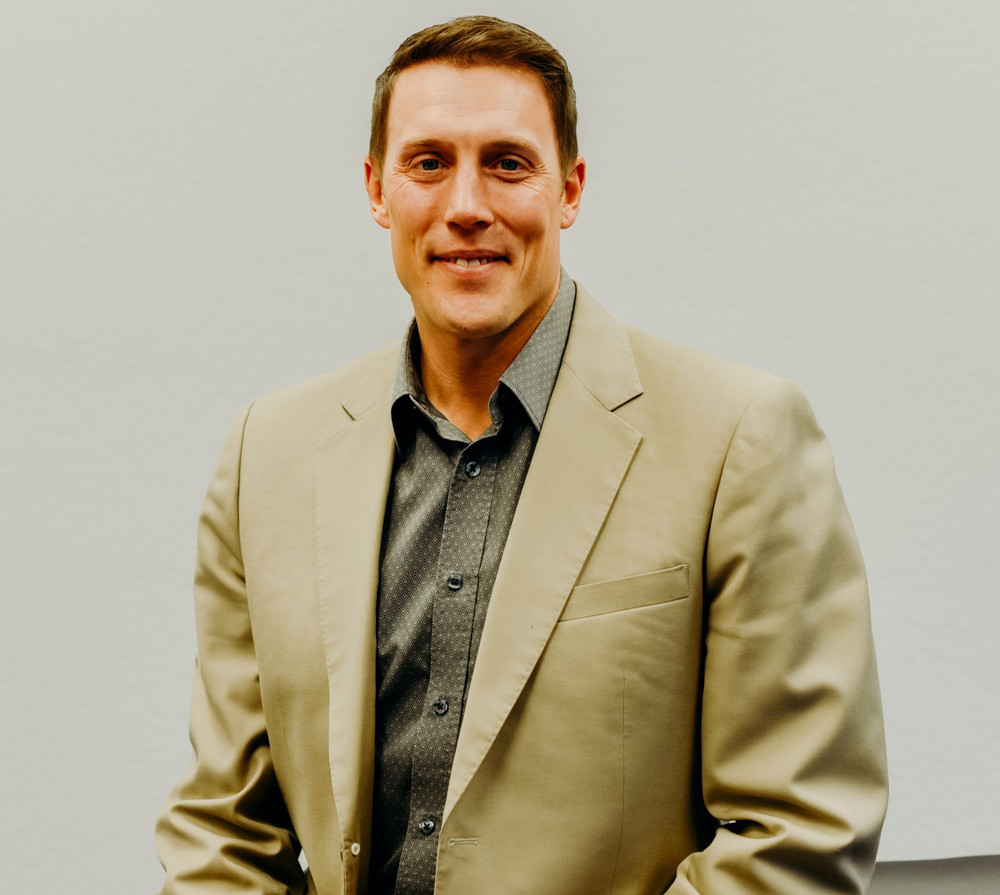 An individual in a beige suit sitting down.