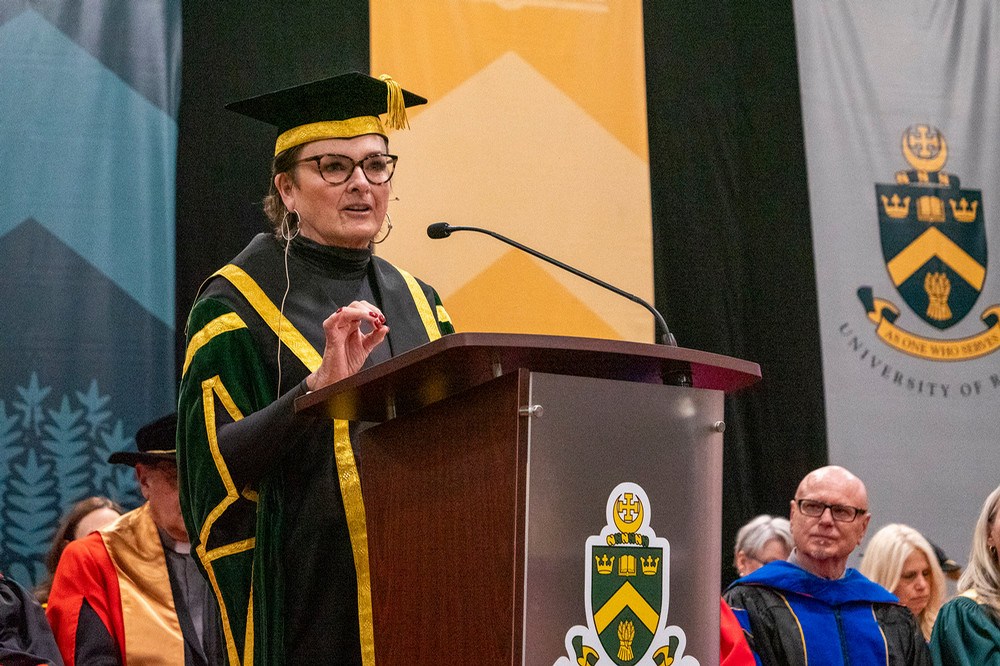 : An individual stands at a podium, speaking to a crowd at convocation.