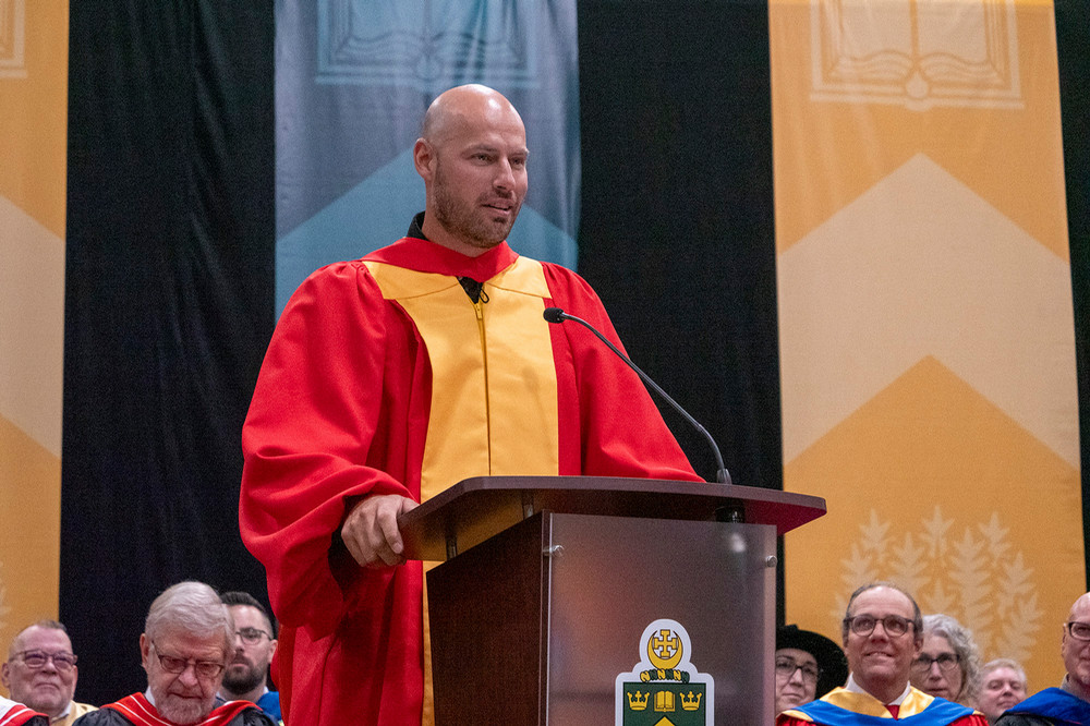 An individual stands at a podium, speaking to a crowd at convocation.