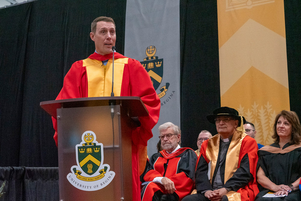 An individual stands at a podium, speaking to a crowd at convocation.