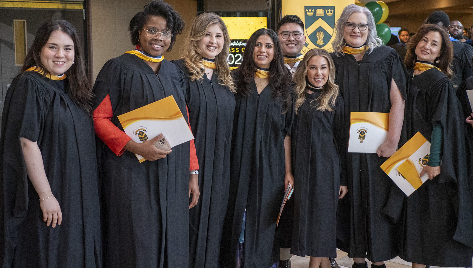 A group of graduates wearing gowns standing side by side.