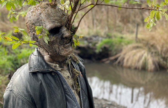 Zombie creature with tree branch growing out the side of his head. 