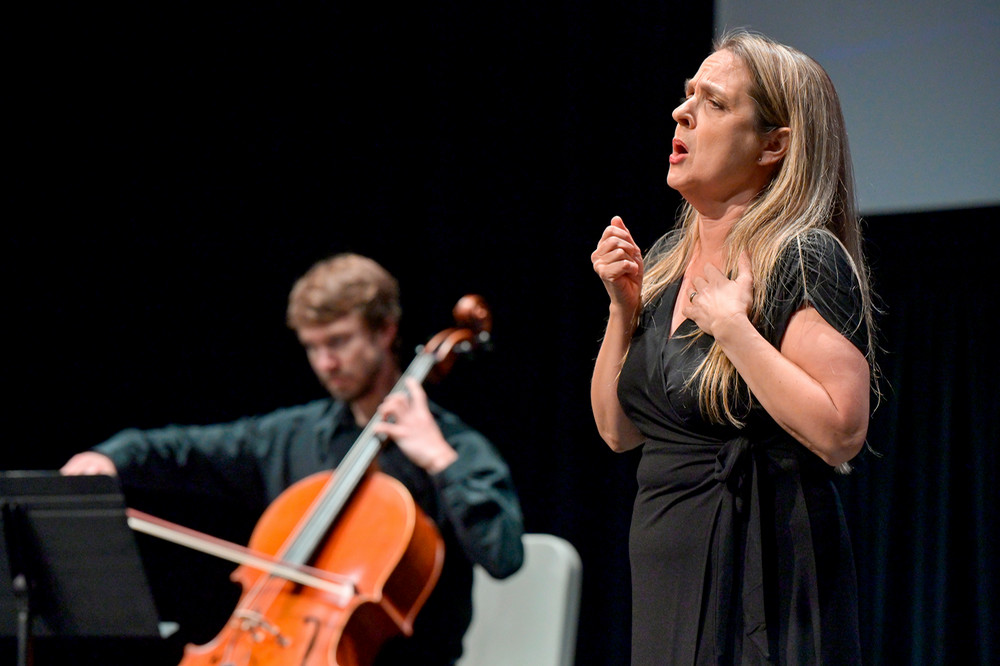 a person singing, while another person plays a cello