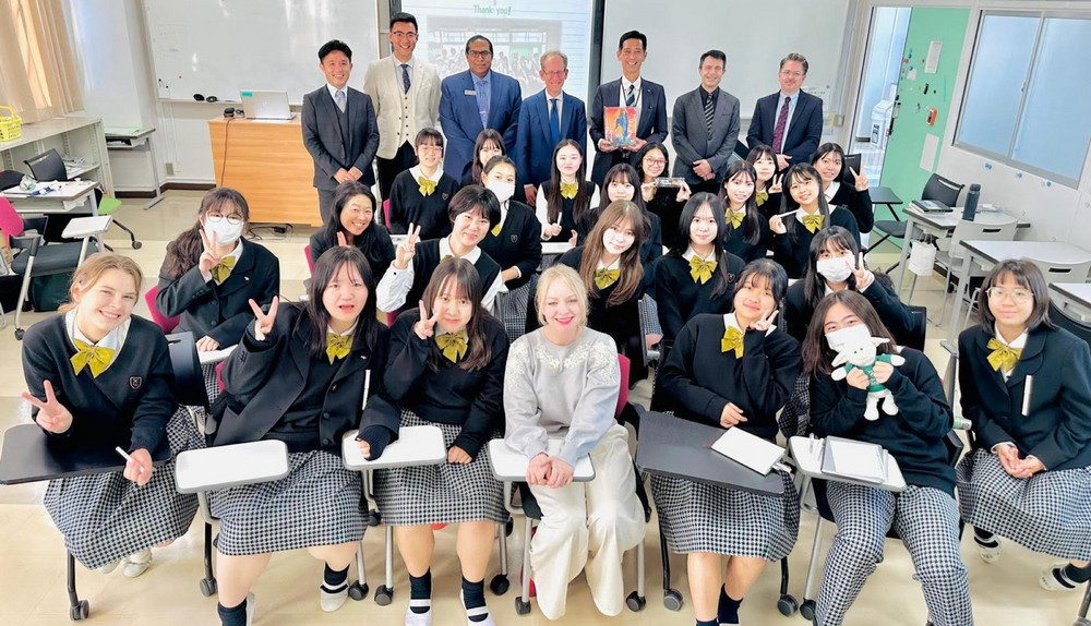 students and delegates pose for a photo in a classroom