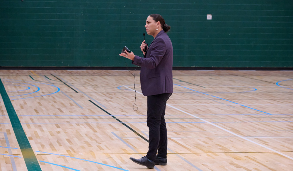 An individual speaking in a university gym.